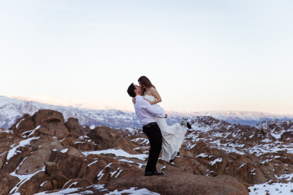 couple on a mountain top kissing while using elopement gear backpacks