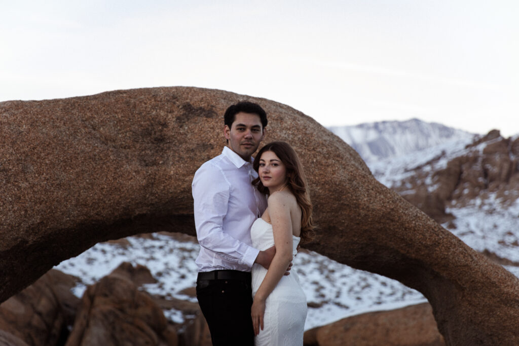 couple posing in front of an arch in Alabama Hills