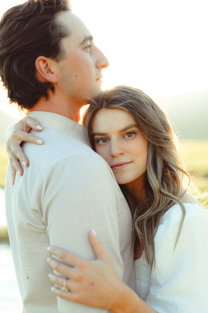 A couple hugging each other and posing for the camera for their engagement photo shoot