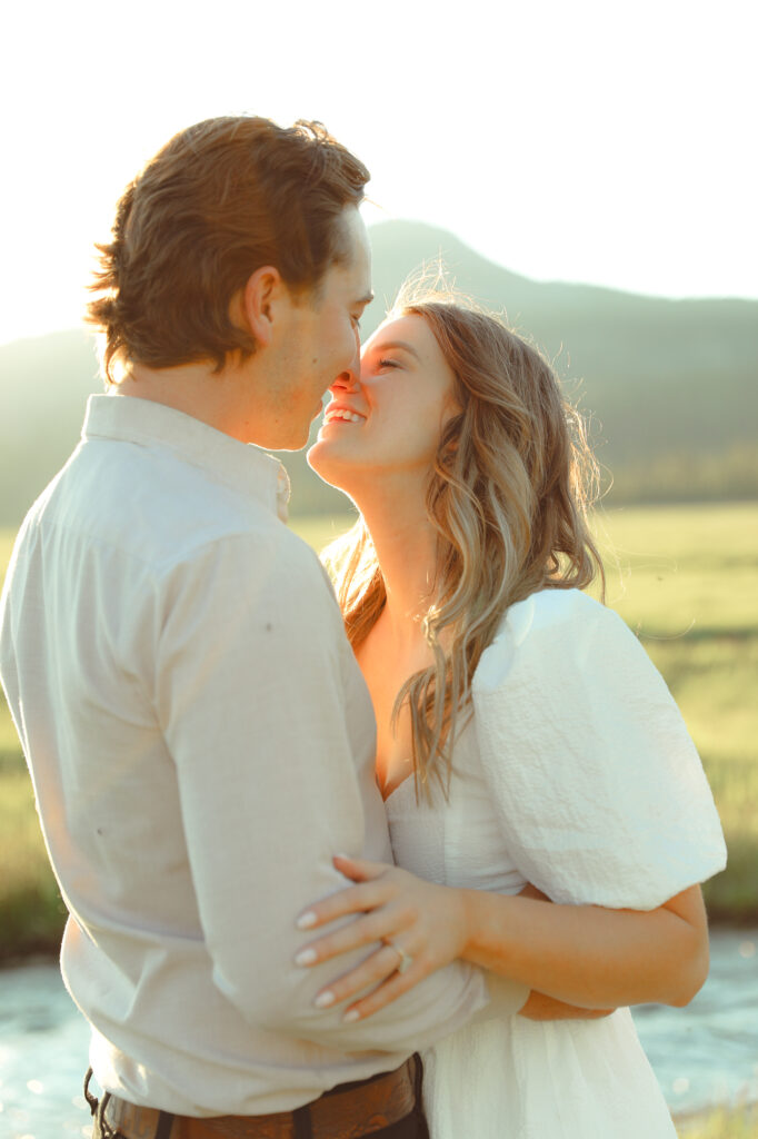 A couple about to kiss in the sunshine to pose for their engagement photo shoot