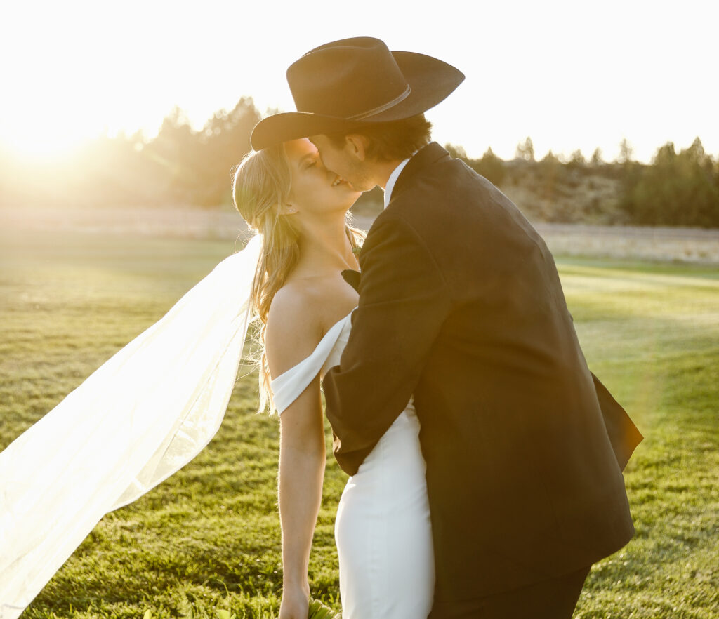 Bride and Groom kissing with the sun behind them for golden hour for their western wedding.